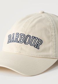 Μπεζ καπέλο μπέιζμπολ με καμπύλη γείσο και κεντημένο μπλε σκούρο κείμενο "BARBOUR" στην μπροστινή πλευρά.