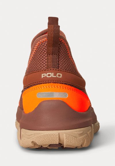 Brauner Sportschuh mit einem strukturierten Mesh-Obermaterial, leuchtend orangefarbenen Akzenten, reflektierenden Elementen und einer robusten, sandfarbenen Außensohle.