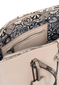 Jasnoróżowa skórzana torebka na zamek błyskawiczny, z wewnętrzną podszewką w wzory, wieloma kieszeniami i odpinanym paskiem.