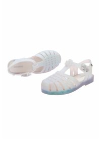 Błyszczące, przezroczyste plastikowe sandały z paskiem, z zamkniętym noskiem i wyciętym wzorem. Kolor zmienia się z białego na jasnoniebieski na podeszwie.