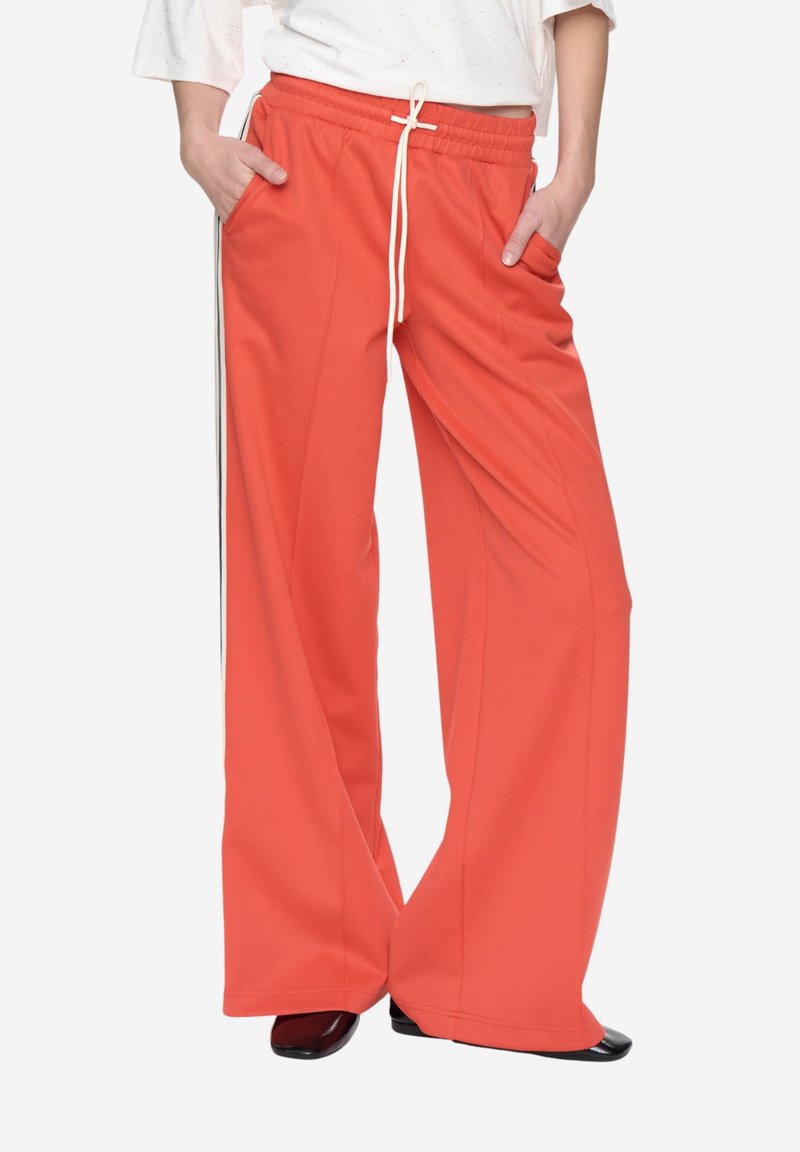 Pantalon à jambes larges en tissu corail vif, doté d'une taille à cordon, de poches latérales et de bandes latérales contrastantes. Texture lisse.