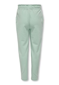 Mintunvihreät jogger-housut, pehmeästä kankaasta valmistetut, löysällä istuvuudella, joustavalla vyötäröllä ja sivutaskuilla. Sileä rakenne ja hillityt yksityiskohdat.