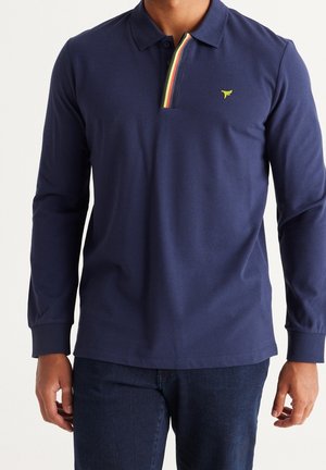 Granatowa koszula polo z długim rękawem, wykonana z bawełny, z paskowanym kołnierzykiem w kolorach zielonym, żółtym i czerwonym, z małym logo na piersi.