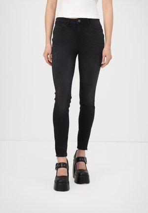 Jeansi negri skinny din denim, cu buzunare frontale și talie medie. Asortați cu pantofi platformă negri, groși, cu bretele.