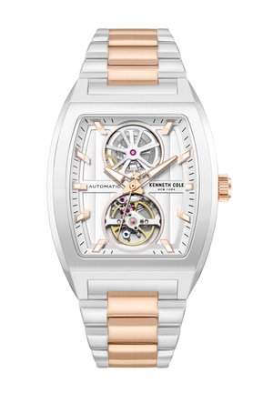 Zilveren en roségouden Kenneth Cole automatische horloge met rechthoekige wijzerplaat, zichtbare tandwielen en metalen schakelarmband.