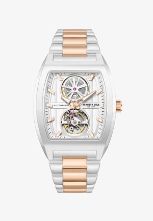 Reloj automático Kenneth Cole de plata y oro rosa con esfera rectangular, engranajes visibles y pulsera de eslabones metálicos.
