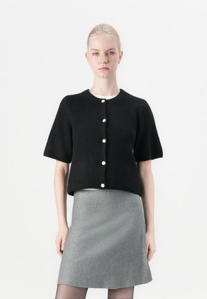 Cardigan negro de punto con mangas cortas y escote redondo, adornado con botones blancos, combinado con una falda gris de línea A. Textura suave, diseño minimalista.