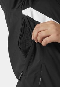 Schwarze Jacke mit einer seitlichen Reißverschlusstasche, ausgestattet mit einem weißen Akzentstreifen, strukturiertem Futter und einem glatten Außenmaterial.