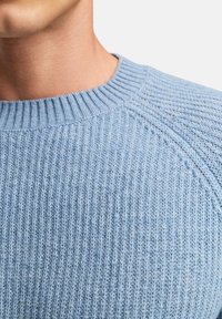 Hellblauer gestrickter Pullover mit geripptem Design, rundem Ausschnitt und Raglanärmeln, versehen mit feinen Nähten und einer weichen Oberfläche.
