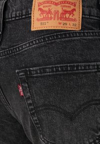 Zwarte denim jeans met een leren label waarop "511" en maatdetails staan. Inclusief rode Levi's-tag op de achterzak en subtiele stikpatronen.