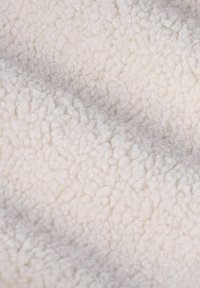 Close-up van zacht, wit, pluizig textiel met kleine, ronde, wolachtige lussen die een gezellige structuur creëren.