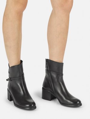 Bottines en cuir noir avec un bout arrondi, une fermeture éclair sur le côté et un talon chunky. Présente une bande en cuir étroite accent autour du haut.