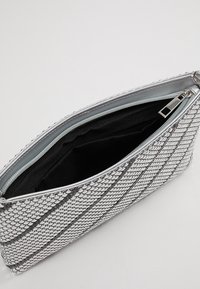 Stříbrná síťová kabelka na zip, s černým interiérem a geometrickým vzorem na vnějším povrchu. Hladký povrch.