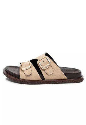 Beżowa sandała typu klapka z dwoma regulowanymi paskami z klamrami oraz ciemnobrązową amortyzowaną podeszwą i wkładką.