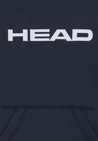 Mornarska kapuca s velikim belim logotipom "HEAD". Ima kenguruv žep i rebrasti rub. Material izgleda meko i glatko.