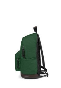 Grön tygryggsäck med svarta detaljer, har ett huvudfack, sidoficka och kontrasterande remmar. Texturerad botten med mörkbrun finish.