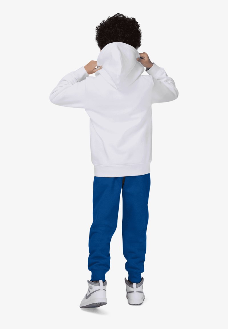 Sudadera blanca con capucha, combinada con pantalones deportivos azules. El conjunto presenta un ajuste relajado, con puños elásticos y zapatillas deportivas a juego.