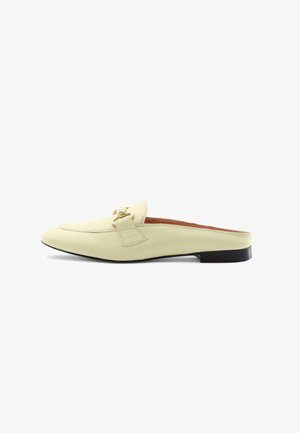 Leather mule in pastel yellow with a flat, dark sole. Features a decorative buckle and stitching accents along the upper edge. Smooth texture.