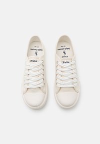 Vita kanvassneakers med en gummitå, som har kontrasterande vita snören över en mjuk foder, präglad "Polo"-logotyp inuti.