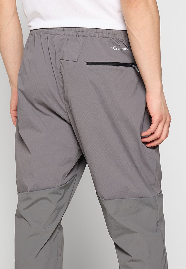 Lekkie, szare spodnie outdoorowe z elastycznym paskiem w talii, zapinaną na zamek tylną kieszenią oraz kontrastującą teksturą dolnej części.