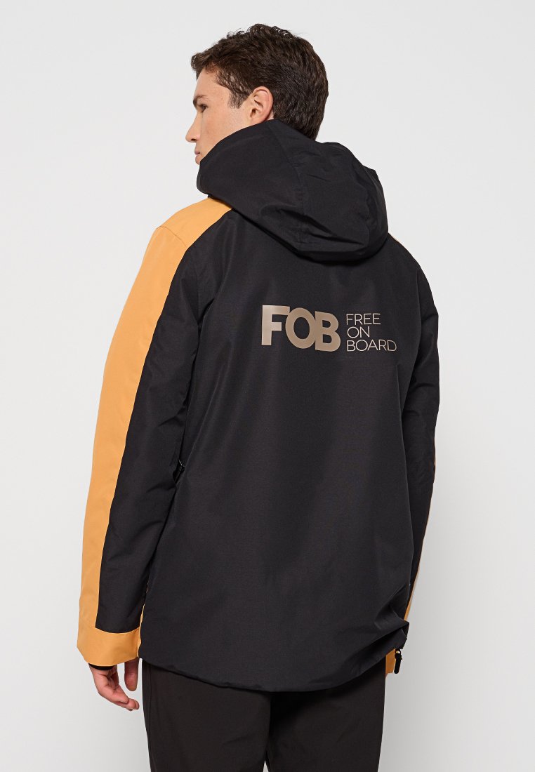 Czarna i pomarańczowa wodoodporna kurtka z kapturem, z dużym logiem "FOB" i napisem "FREE ON BOARD" na plecach. Gładka tekstura i sportowy design.