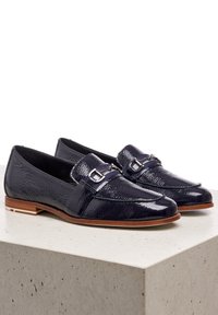 Navy patent leather loafers with a textured finish, featuring a refined strap with silver-toned hardware and a low stacked heel.