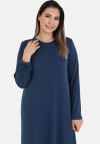 Long-sleeve dress in navy blue fabric, featuring a round neckline and relaxed fit. Smooth texture with minimal seams and detailing.
