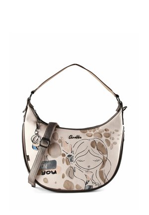 Beigefarbene Halbmond-Handtasche mit braunen Akzenten, verstellbarem Riemen, Anhänger und Illustration eines Mädchens, das einen Eistüte hält, umgeben von abstrakten Flecken.