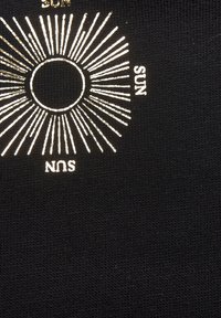 Schwarzer Stoff mit metallic-goldenem Sonnenmotiv und strahlenden Linien. Der Text "SONNE" erscheint in Gold neben dem Design.