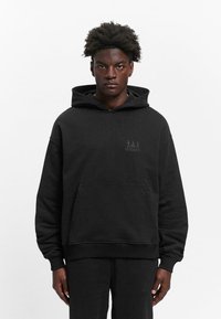 Black hooded sweatshirt made of cotton, featuring a front pocket, ribbed cuffs, and a small graphic logo printed in dark gray.