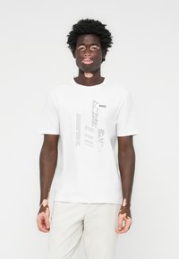 Witte katoenen t-shirt met een grafisch ontwerp in het zwart met het woord "BOSS." Korte mouwen en een ronde halsstijl. Gladde textuur.