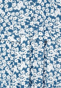 Tissu bleu à petits imprimés floraux blancs, boutons bleus au centre et ceinture assortie nouée à la taille.