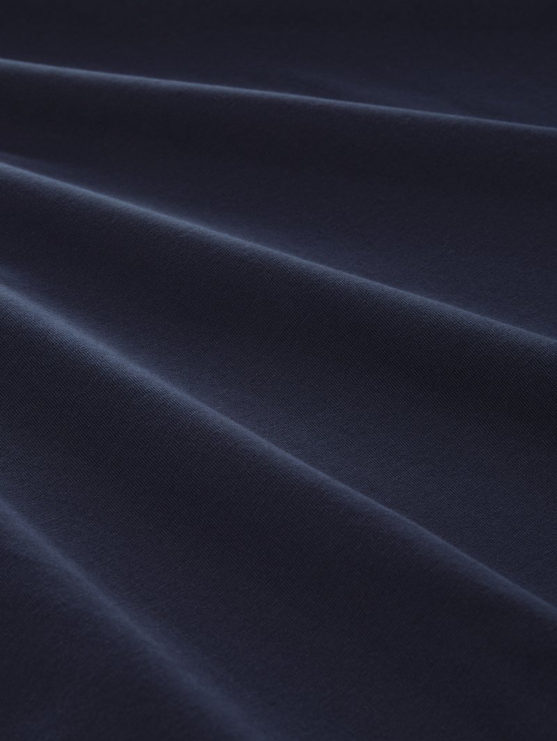 Granatowy bawełniany materiał o gładkiej fakturze i widocznych fałdach, charakteryzujący się jednolitą barwą z delikatnym połyskiem odbijającym światło.