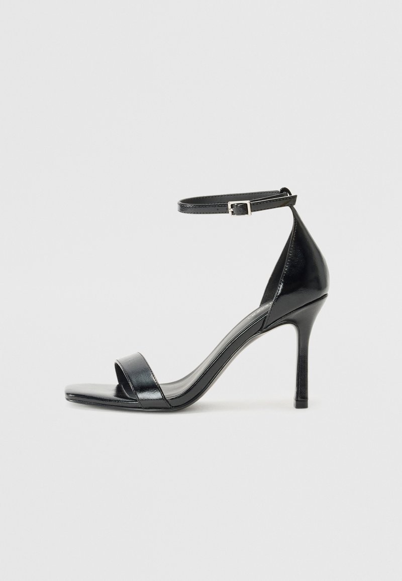 Black patent leather high-heeled sandal with an open toe, a single strap across the front, and an adjustable ankle strap.