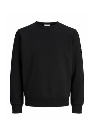 Sweat-shirt noir à col rond, manches longues, poignets et ourlet côtelés, et une petite pièce noire sur la manche gauche. Aucun logo visible sur le devant.