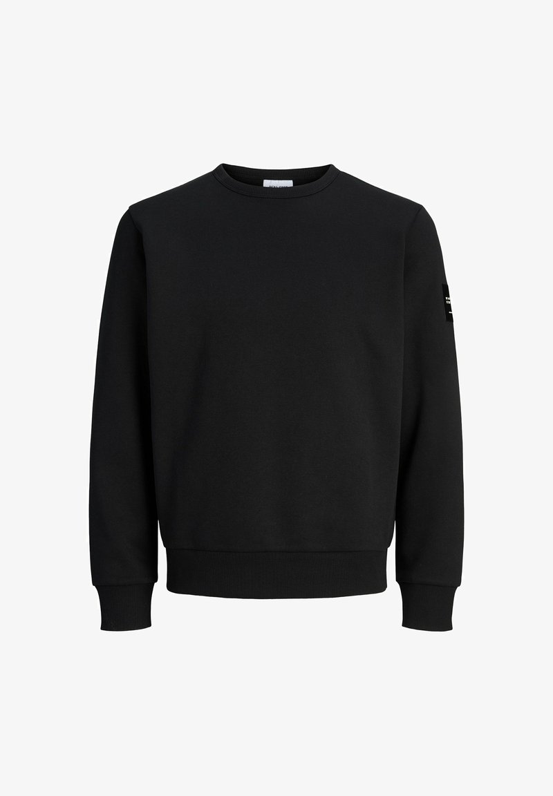 Sweat-shirt noir à col rond, manches longues, poignets et ourlet côtelés, et une petite pièce noire sur la manche gauche. Aucun logo visible sur le devant.