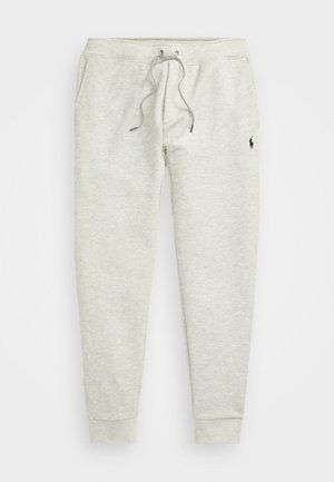 Pilkos jogger kelnės su raišteliu juosmenyje, elastingais rankogaliais, šoninėmis kišenėmis ir maža logotipų etikete kairėje šlaunies pusėje. Minkšta audinio tekstūra.
