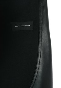 Parche textil negro con un borde suave similar al cuero, que presenta letras blancas: ''MWM'' x mod wave movement. Superficie texturizada, diseño minimalista.