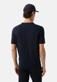 Marineblaues Kurzarm-Strickshirt mit Rundhalsausschnitt und umgeschlagenen Ärmeln, aus glattem Stoff gefertigt, mit klaren Linien und einem minimalistischen Design.