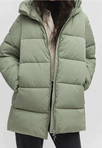 Hellgrüne Steppjacke mit Kapuze, die horizontale Steppabschnitte, einen Frontreißverschluss und Seitentaschen aufweist. Strukturierte Oberfläche, lässiges Design.