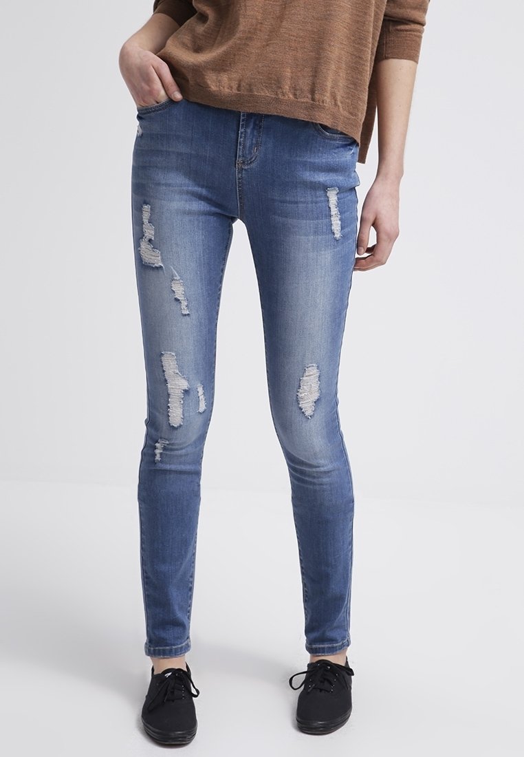 Jeans skiny azul deslavado con parches desgastados, que cuentan con un clásico diseño de cinco bolsillos y una tela con un ligero estiramiento para mayor comodidad.