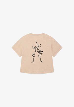 T-shirt beige à manches courtes présentant un dessin au trait noir au dos. Texture douce, coupe décontractée et encolure arrondie.