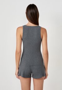 Top de tirantes gris con un escote redondeado, combinado con pantalones cortos de canalé a juego. Textura suave y diseño ajustado.