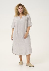 Abito a righe, lungo fino al ginocchio, realizzato in tessuto leggero, con scollatura a V, maniche corte e spacchi laterali. Presenta sottili linee verticali in beige e marrone.