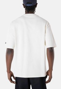 T-shirt à manches courtes, col rond, en coton blanc. Présente une coupe décontractée et un petit logo sur la manche gauche.