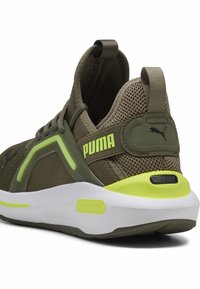 Olivově zelené tenisky s síťovaným svrškem, neonově žlutými akcenty, polstrovanou bílou podrážkou a poutkem na zadní straně. Na boku je logo.