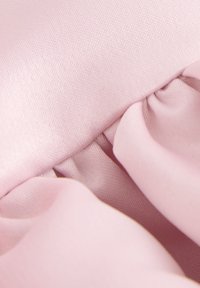 Ljusrosa tyg med en slät yta, med rynkiga sektioner som skapar mjuka veck. Materialet verkar lätt och smidigt.