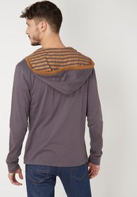 Camiseta de manga larga gris con capucha a rayas marrón. Presenta un corte holgado con costuras simples y sin marcas visibles.