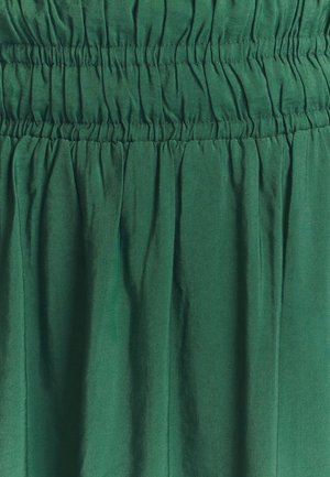 Falda de tela verde con cinturilla elástica fruncida, que presenta una textura suave y ligera y un suave drapeado.