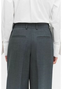 Grå skräddarsydda byxor har en elegant design med en slät textur, raka ben och två bakfickor. Midjebandet har bältes�öglor.